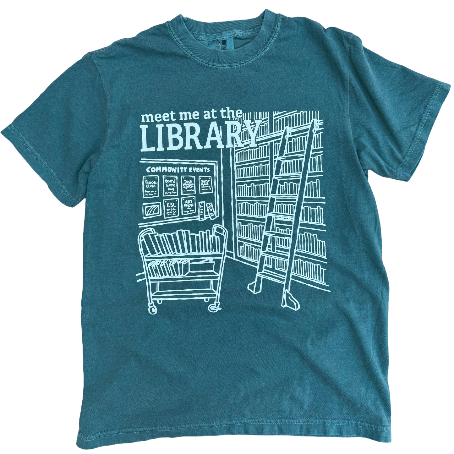 Teal t-shirt with white library graphic and text 'meet me at the LIBRARY'.